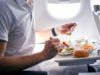 A man eating a meal while sitting on a plane