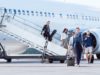 People walking down the stairs of a plane