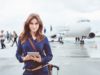 A women with a tablet in her hands standing next to a plane